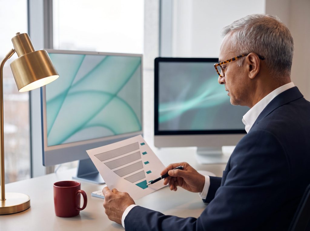 M&A advisory managing partner reviewing a printed mandate funnel report that measures lead generation from search